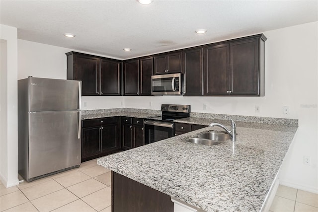 kitchen with appliances with stainless steel finishes, dark brown cabinetry, kitchen peninsula, and sink