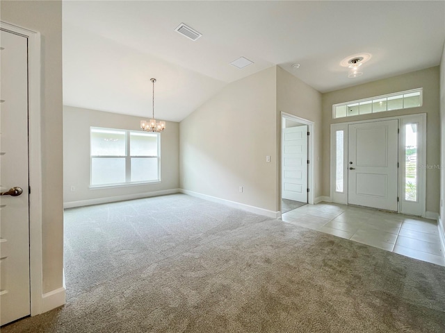 foyer entrance with vaulted ceiling, light carpet, and a chandelier