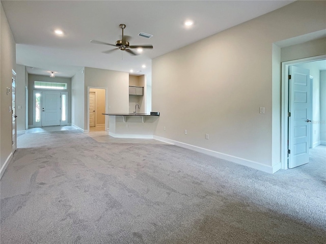 unfurnished living room with light carpet, ceiling fan, and sink