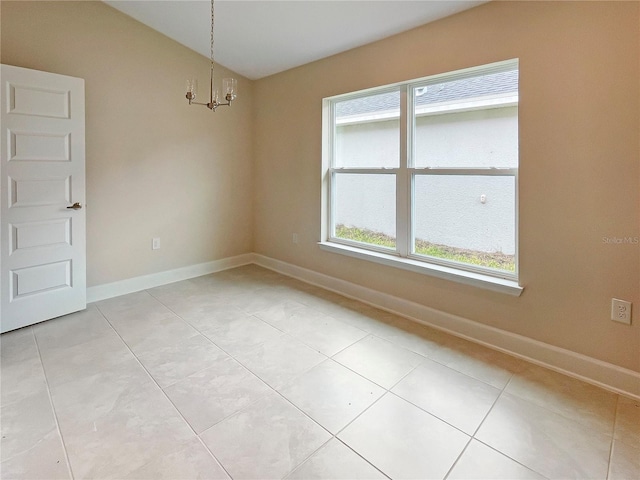 tiled spare room featuring an inviting chandelier