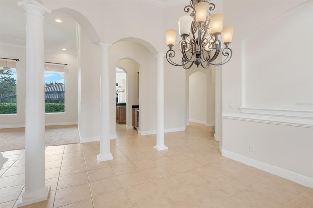 interior space with decorative columns, ornamental molding, an inviting chandelier, and light tile patterned flooring