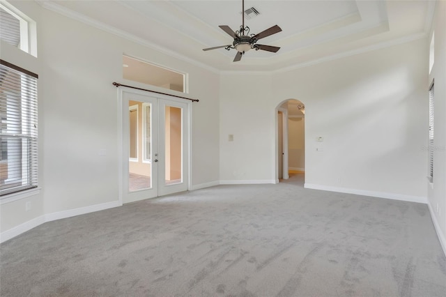 carpeted spare room with ceiling fan, a raised ceiling, ornamental molding, and a high ceiling