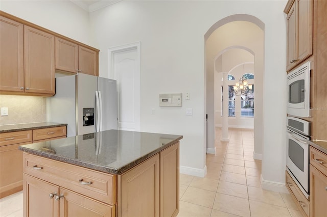 kitchen featuring dark stone countertops, a notable chandelier, stainless steel appliances, and a kitchen island