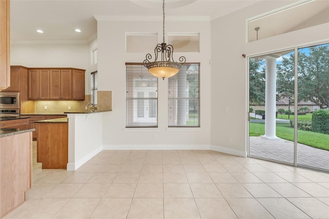 kitchen with light tile patterned floors, pendant lighting, stainless steel appliances, and a wealth of natural light