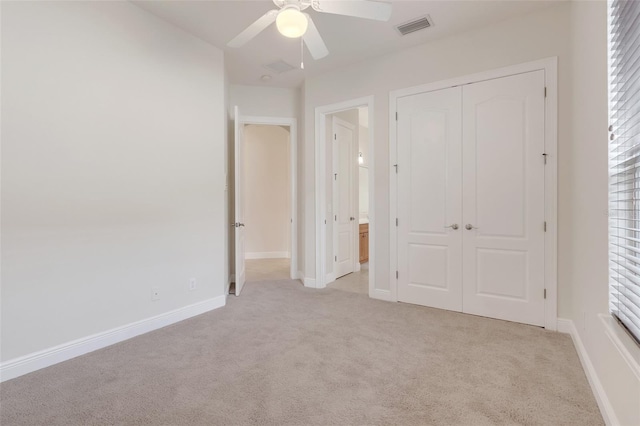 unfurnished bedroom with multiple windows, ceiling fan, light colored carpet, and a closet