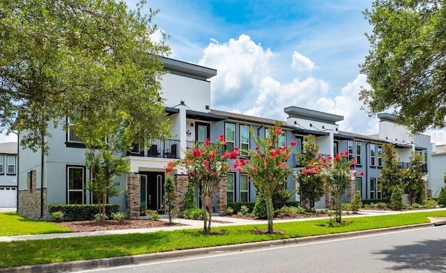 view of front of home featuring a balcony and a front lawn