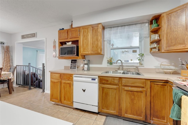 kitchen with a textured ceiling, sink, dishwasher, range, and light tile patterned flooring