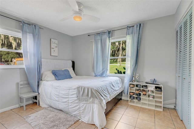 tiled bedroom with ceiling fan, a textured ceiling, and a closet