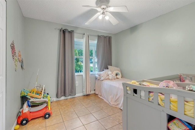 bedroom featuring light tile patterned floors, a ceiling fan, and a textured ceiling