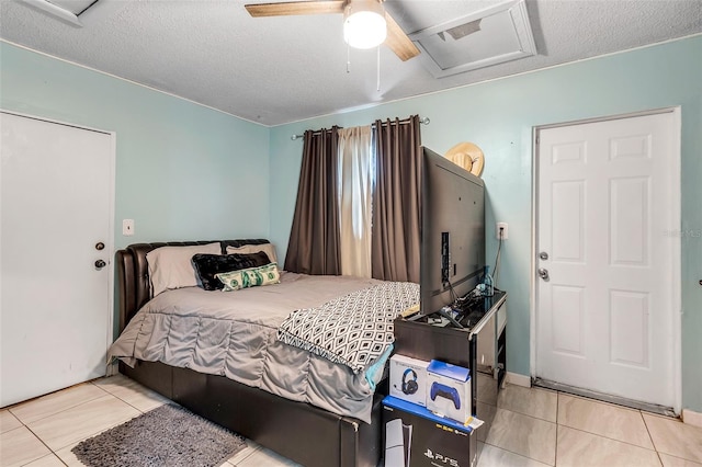 tiled bedroom featuring ceiling fan, attic access, and a textured ceiling