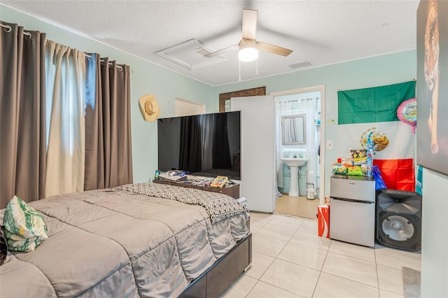 tiled bedroom with fridge, a textured ceiling, ensuite bathroom, and ceiling fan