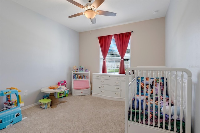 carpeted bedroom featuring ceiling fan and a crib