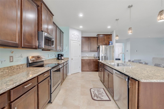 kitchen featuring a center island with sink, sink, pendant lighting, and stainless steel appliances