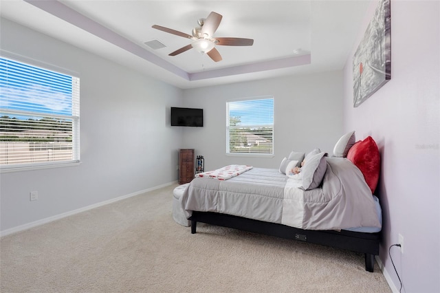 carpeted bedroom featuring a tray ceiling and ceiling fan