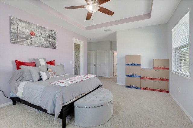 carpeted bedroom with a tray ceiling and ceiling fan