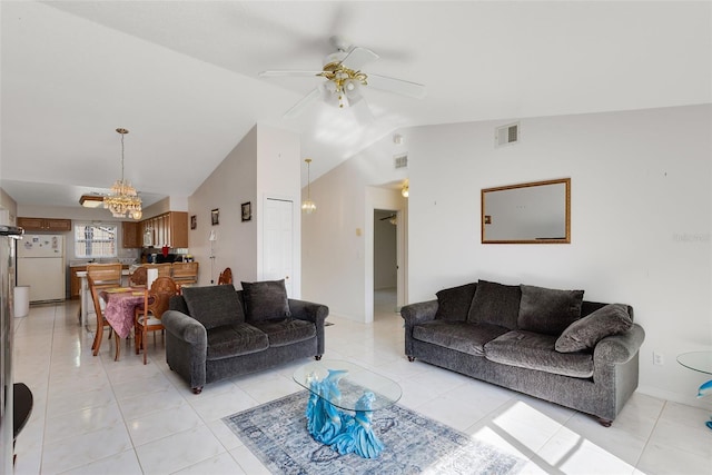 living room featuring ceiling fan with notable chandelier, light tile patterned flooring, and vaulted ceiling