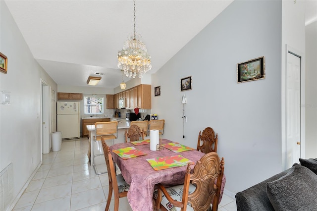 tiled dining space featuring vaulted ceiling and a chandelier