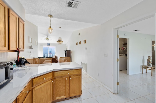 kitchen featuring a textured ceiling, light tile patterned flooring, lofted ceiling, kitchen peninsula, and hanging light fixtures