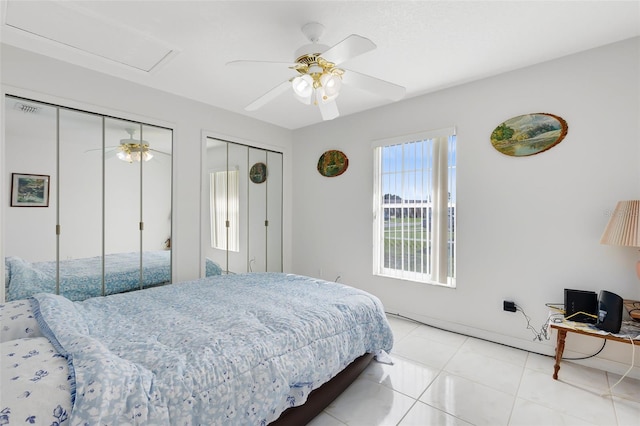 bedroom with light tile patterned floors, ceiling fan, and multiple closets