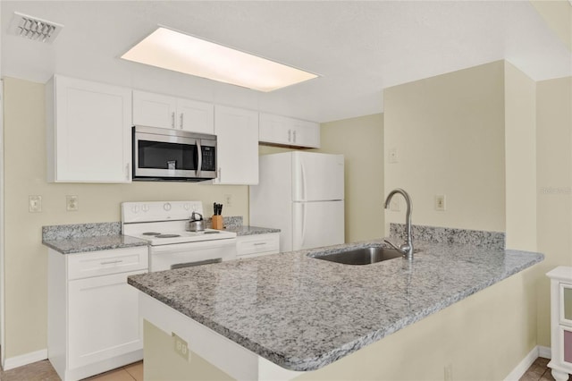 kitchen featuring white cabinetry, white appliances, kitchen peninsula, light tile patterned floors, and sink