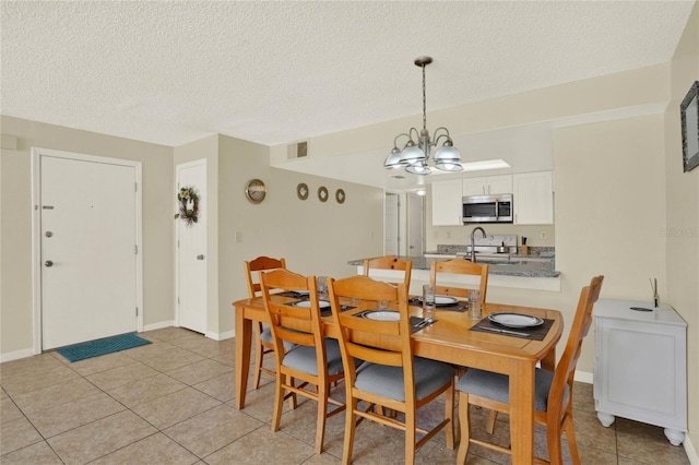 tiled dining area with a notable chandelier and a textured ceiling