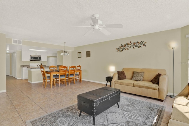 living room featuring ceiling fan with notable chandelier, a textured ceiling, and light tile patterned floors