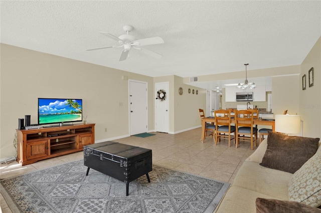 tiled living room featuring a textured ceiling and ceiling fan with notable chandelier