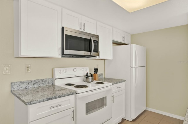 kitchen with light stone counters, white cabinets, light tile patterned floors, and white appliances