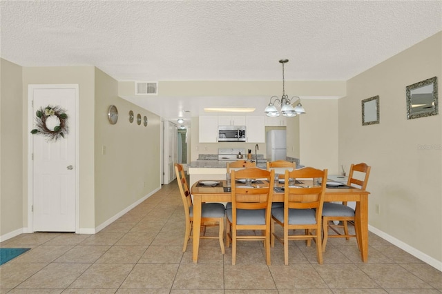 dining space featuring a textured ceiling, an inviting chandelier, and light tile patterned floors