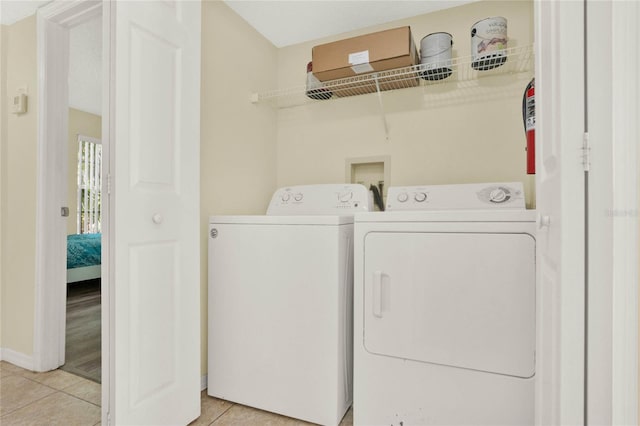 clothes washing area featuring washer and clothes dryer and light tile patterned floors