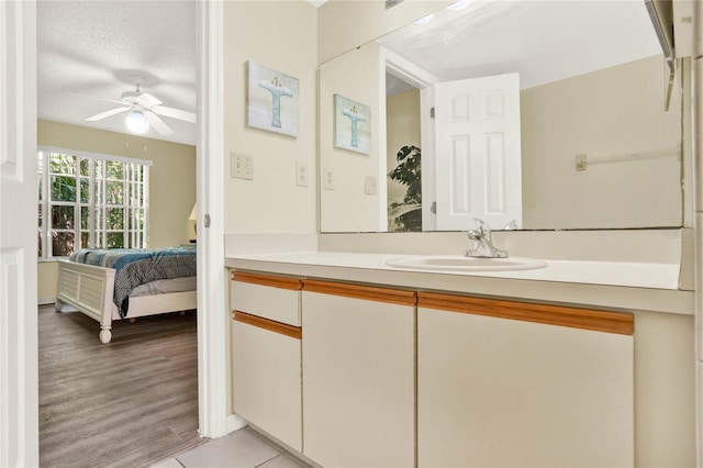 bathroom featuring hardwood / wood-style floors, ceiling fan, vanity, and a textured ceiling