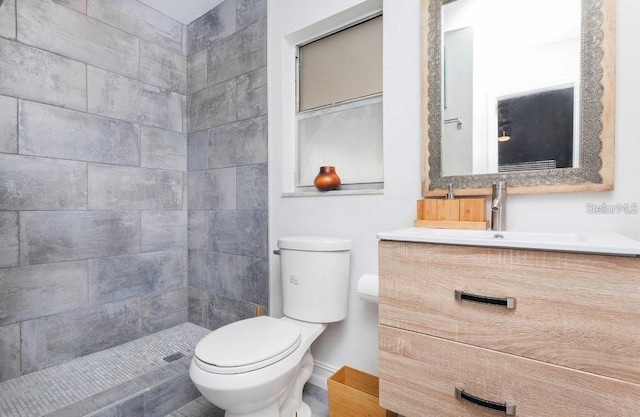 bathroom with a tile shower, vanity, and toilet