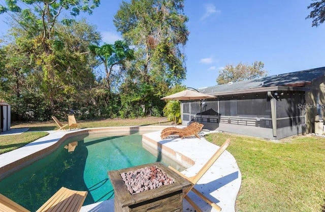 view of pool featuring a sunroom, a patio area, an outdoor fire pit, and a yard