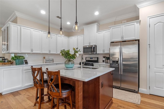 kitchen featuring backsplash, hanging light fixtures, stainless steel appliances, and light wood-type flooring