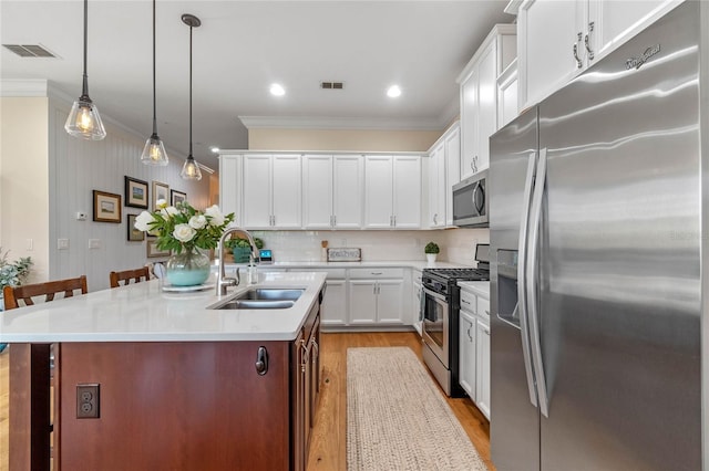 kitchen featuring a kitchen island with sink, sink, white cabinets, a kitchen bar, and stainless steel appliances