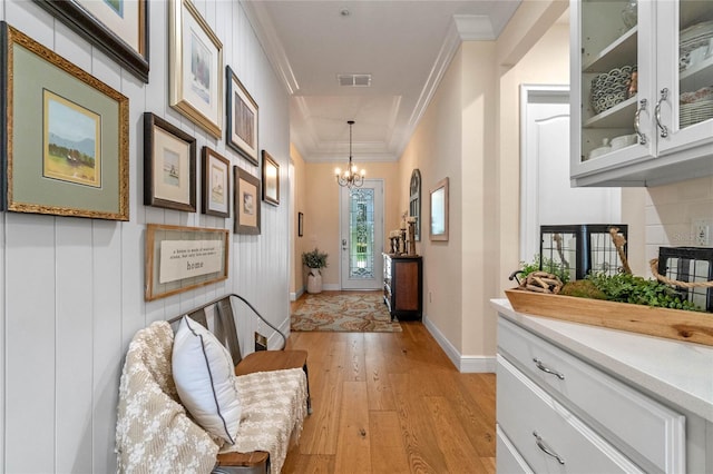 hall featuring a notable chandelier, light wood-type flooring, and crown molding