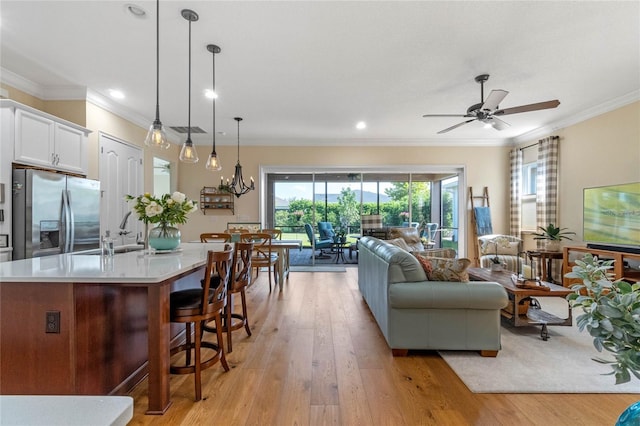 living room featuring light wood-type flooring, ceiling fan, sink, and crown molding