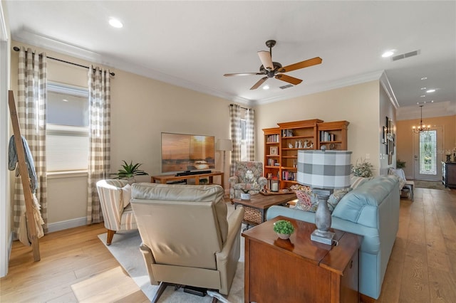 living room with ceiling fan with notable chandelier, light hardwood / wood-style flooring, ornamental molding, and a healthy amount of sunlight