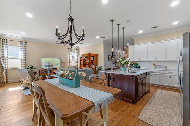 dining space with crown molding, light hardwood / wood-style floors, sink, and a chandelier