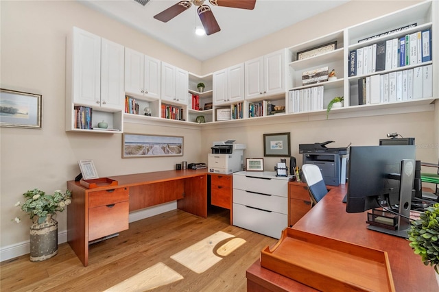 home office with light wood-type flooring, ceiling fan, and built in desk