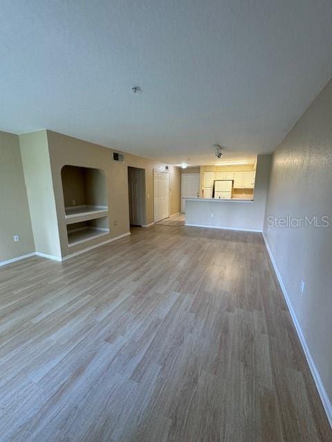 unfurnished living room featuring wood-type flooring and built in features