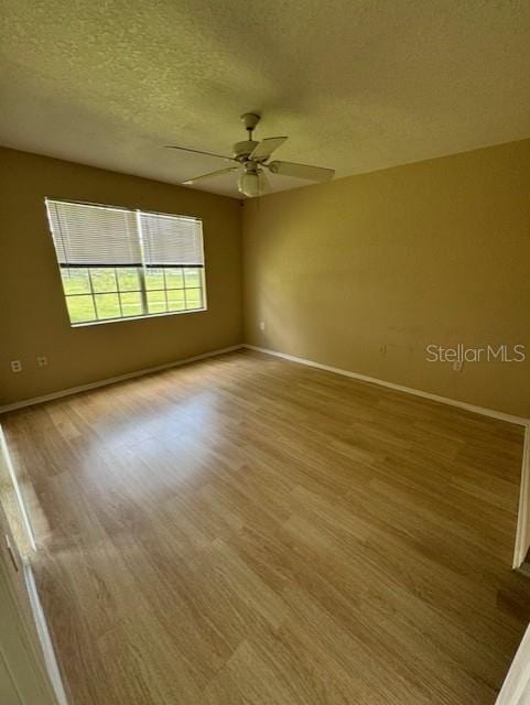 empty room featuring light hardwood / wood-style flooring, ceiling fan, and a textured ceiling