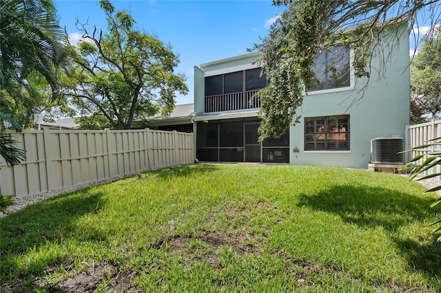 back of property featuring stucco siding, a sunroom, central AC, and a fenced backyard