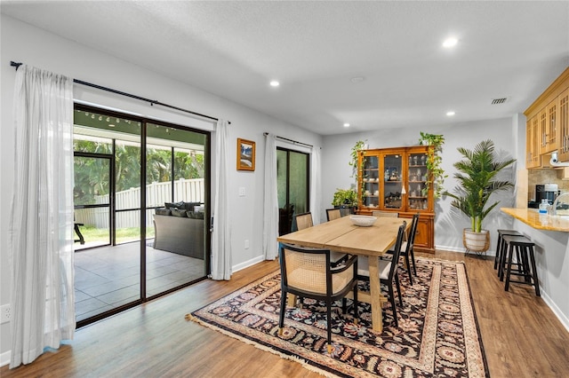dining space with baseboards, visible vents, wood finished floors, and recessed lighting