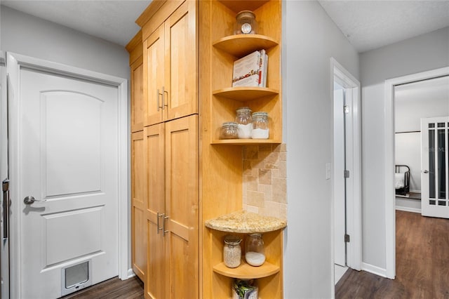 interior space with light stone counters, open shelves, tasteful backsplash, baseboards, and dark wood-style flooring