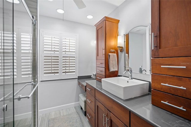 bathroom with a ceiling fan, vanity, a stall shower, and baseboards