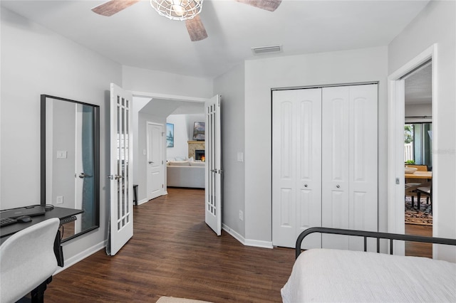 bedroom with a closet, visible vents, baseboards, a ceiling fan, and dark wood-style floors