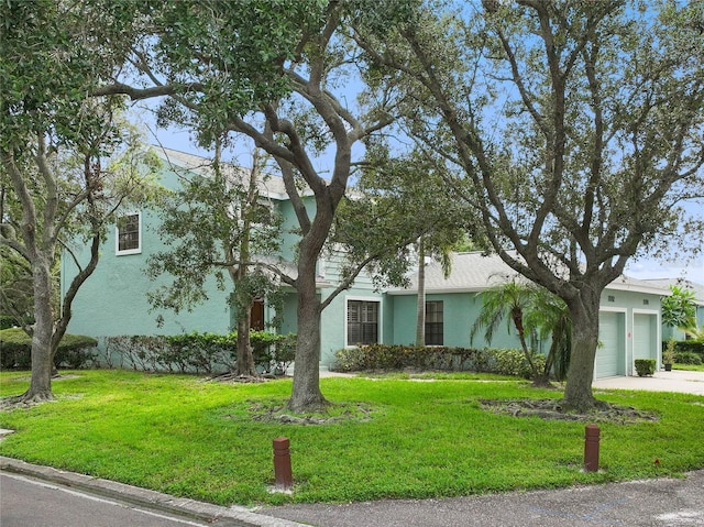 view of front facade with a front yard, concrete driveway, stucco siding, and an attached garage