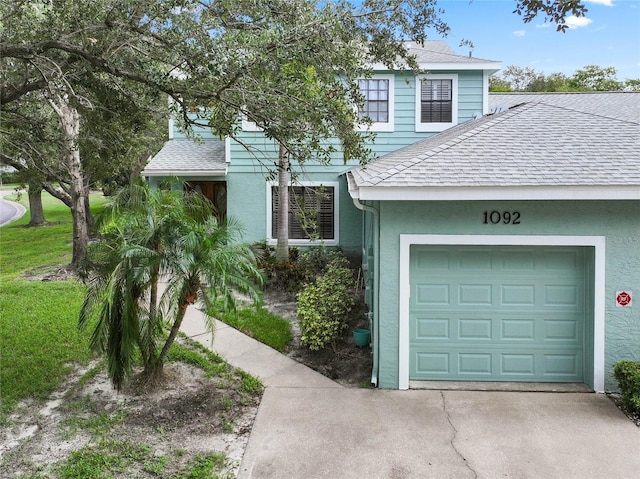 view of front of property featuring a shingled roof, driveway, stucco siding, and an attached garage
