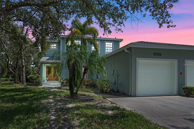 view of front facade with stucco siding, an attached garage, and concrete driveway